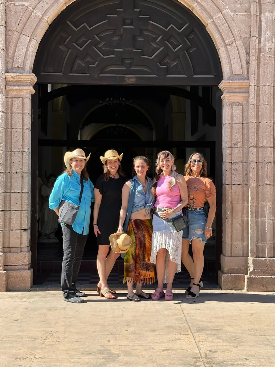 Five people standing together in front of the carved wooden door of the stone mission church in Loreto